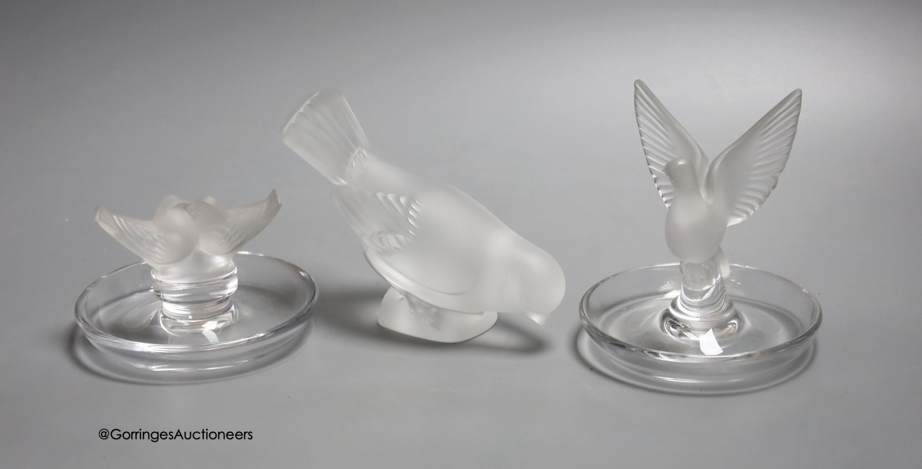 Two Lalique ashtrays mounted with birds, etched signatures to bases, and a Lalique style frosted glass bird paperweight